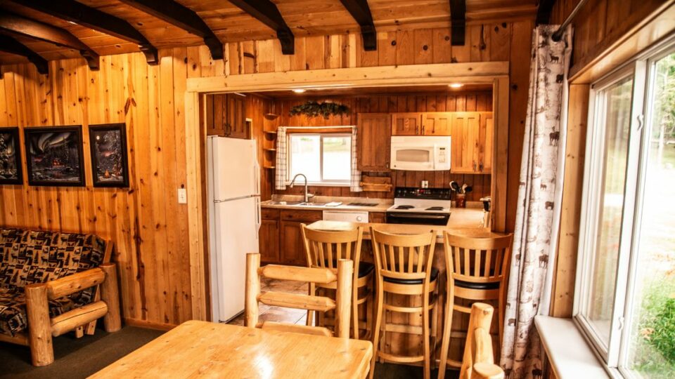 Cabin Rental 10 Interior Kitchen, Countertop and Barstools, and Dining Table.
